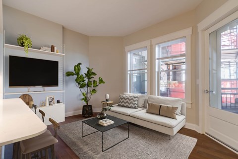 A living room with a white couch, a coffee table, and a flat screen TV.