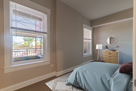 A bedroom with a bed, nightstand, and window with blinds.