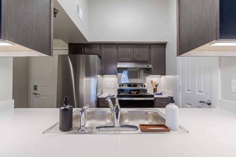 A modern kitchen with a double sink and a stainless steel refrigerator.