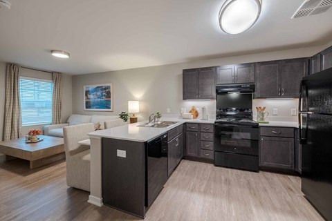 A modern kitchen with black cabinets and a white island.