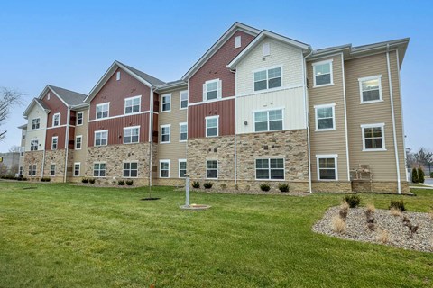 A large apartment complex with multiple buildings and a grassy front yard.
