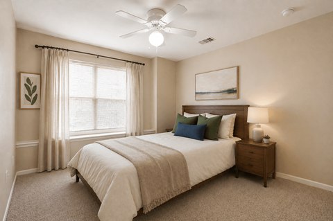 A bedroom with a large bed, a ceiling fan, and a window with curtains.