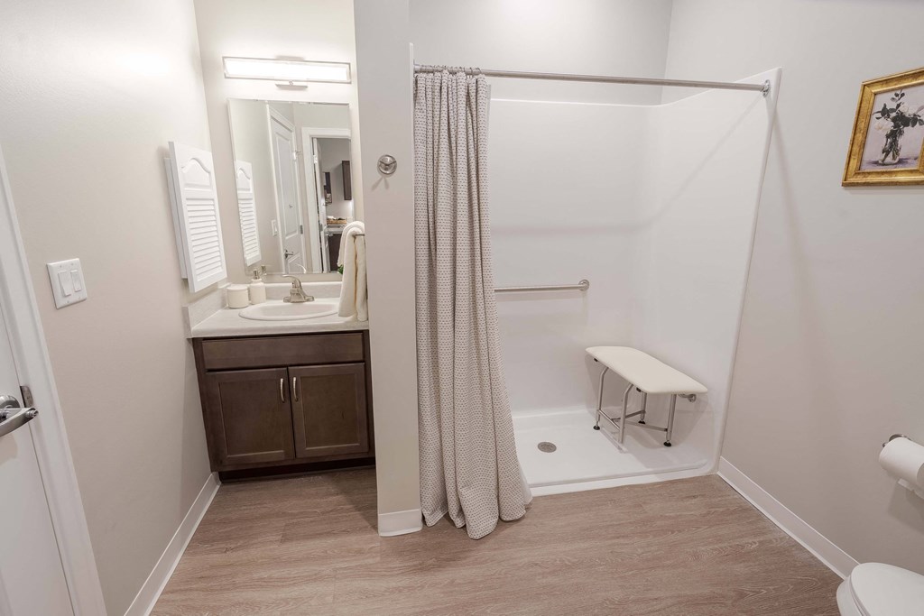 A bathroom with a white toilet, a sink with a mirror and a brown cabinet.