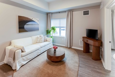 A living room with a white couch, a coffee table, and a painting on the wall.