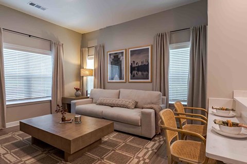 A living room with a grey couch, a coffee table, and a dining table set for two.