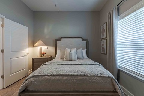 A bedroom with a large bed and a nightstand with a lamp.