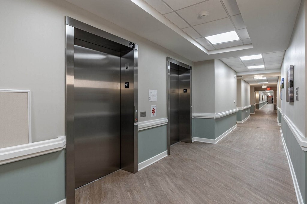 A long hallway with two elevators on the left side.