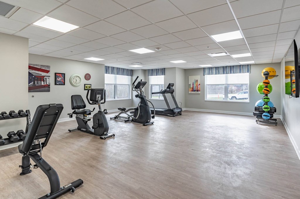 A gym with a variety of exercise equipment including treadmills, stationary bikes, and elliptical machines.