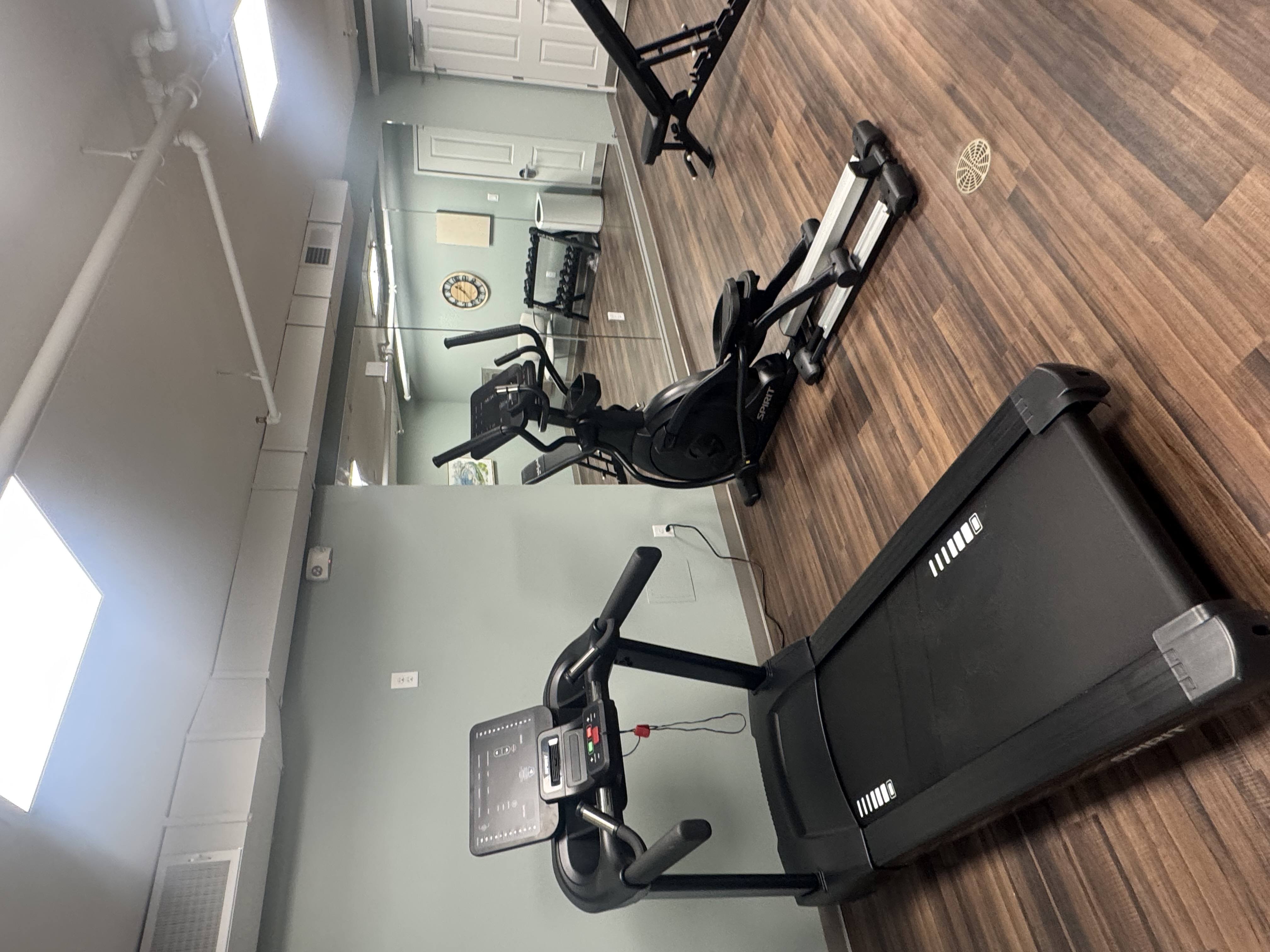 A treadmill and a stationary bike are in a gym.