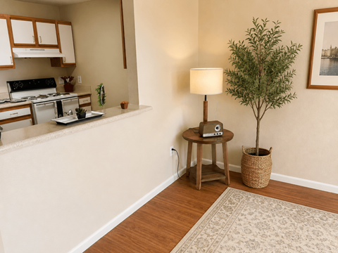A small tree in a basket sits on a table next to a lamp in a kitchen.