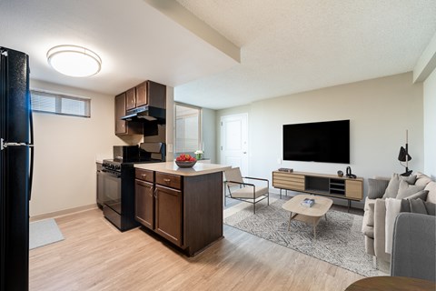 A modern kitchen with dark wood cabinets and a black refrigerator.