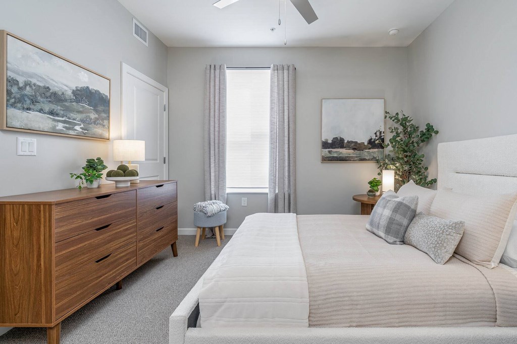 A bedroom with a large bed, a dresser, and a painting on the wall.