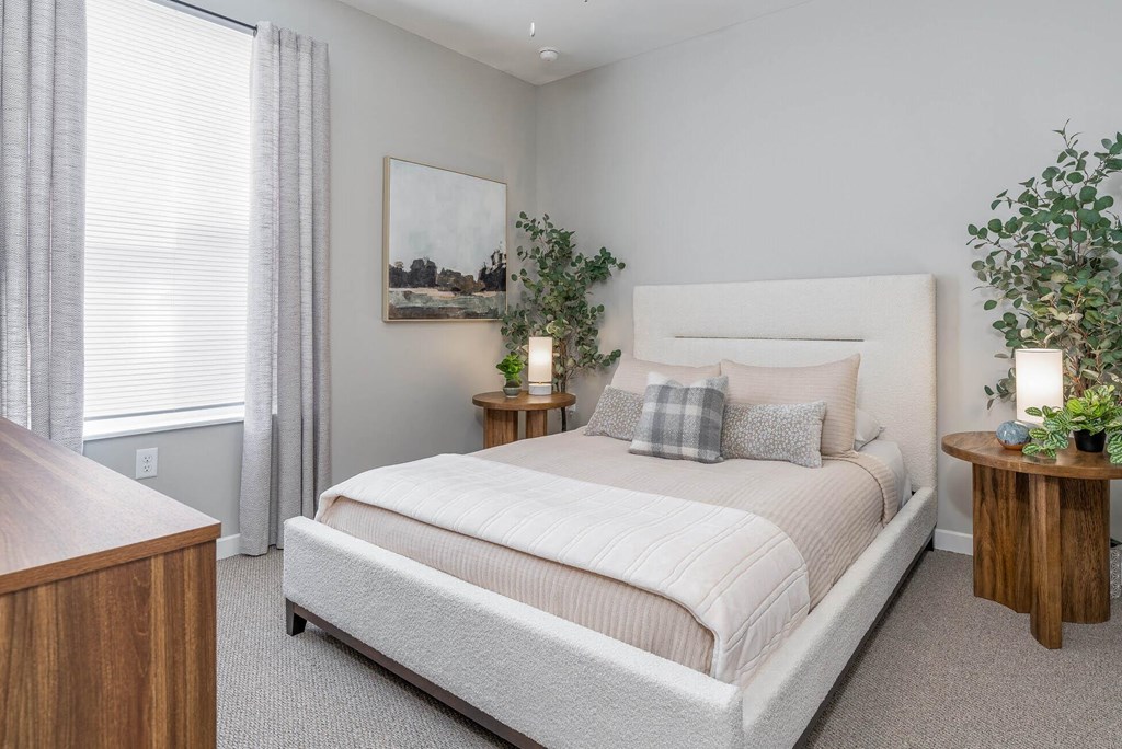 A bedroom with a large bed, a wooden nightstand, and a painting on the wall.