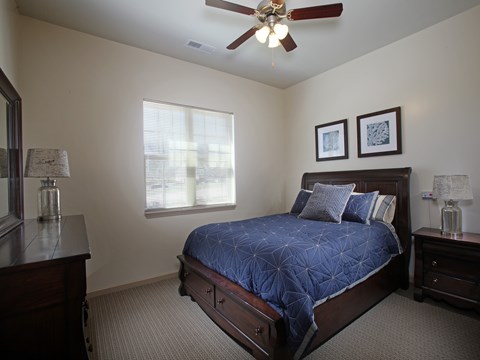A bedroom with a bed, nightstands, and a ceiling fan.