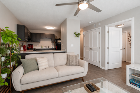 A living room with a beige couch and a ceiling fan.