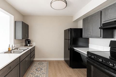 A kitchen with black appliances and wooden floors.