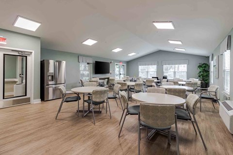A spacious room with tables and chairs and a television.