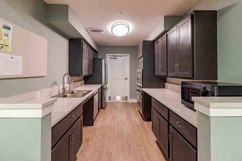 A kitchen with dark brown cabinets and light wood floors.