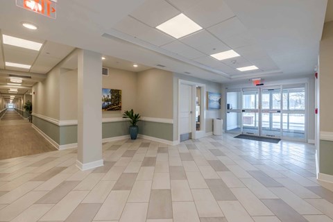 A long hallway with a tile floor and white pillars.
