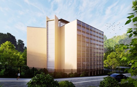 A modern building with a glass facade is surrounded by greenery and a black fence.