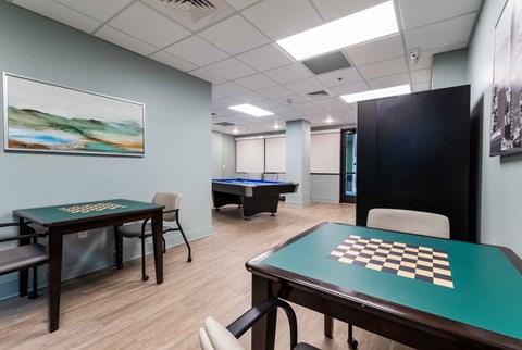 A room with a chess board on a table and a pool table in the background.