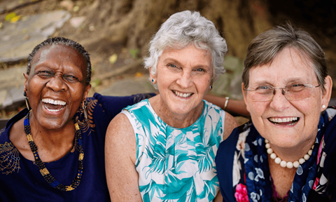 Three women are sitting together and smiling.
