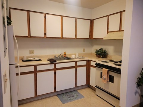 A kitchen with white cabinets and a white refrigerator.