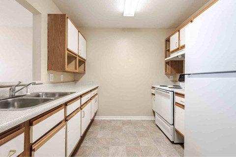 A kitchen with white appliances and wooden cabinets.
