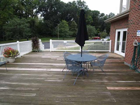 A patio with a table and chairs and a black umbrella.
