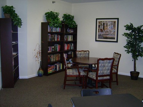 A room with a bookcase, a table and chairs.