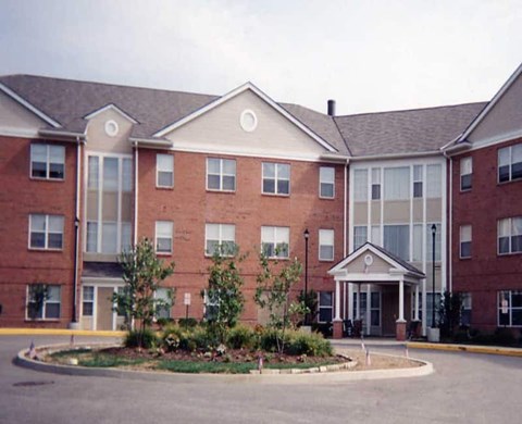 A large red brick building with a landscaped front yard.