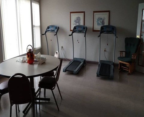 A room with a table, chairs and exercise equipment.