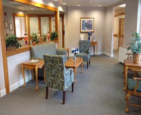 A room with a green chair and a table with a vase of flowers on it.