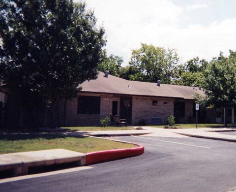 A building with a brown roof and a tree in front of it.