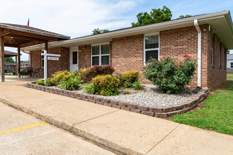 A small brick building with a porch and a sign that says "OFFICE" on it.