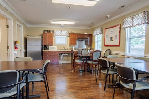A kitchen with a table and chairs in the foreground and a refrigerator in the background.