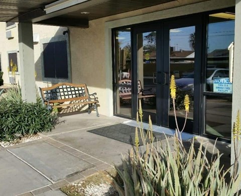 A bench is placed outside a building with glass doors.