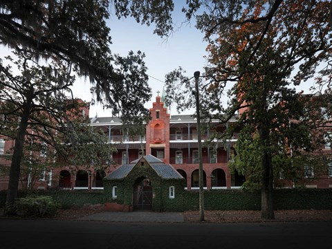 A red building with a tower and a gate in front.