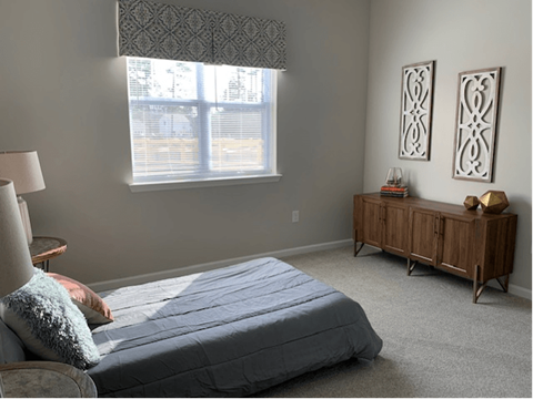 A bedroom with a bed, nightstand, and window.