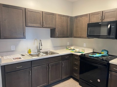 A kitchen with brown cabinets and a black stove top oven.