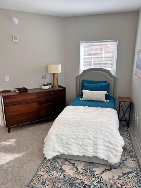 A bedroom with a bed, nightstand, and lamp.