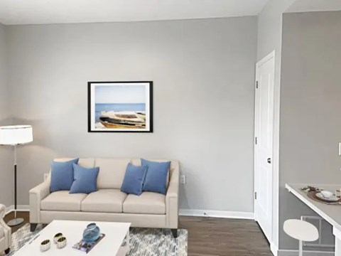 A living room with a white couch and a painting on the wall.