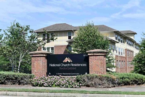 The image shows a sign for National Church Residences Pinehursts in front of a building.