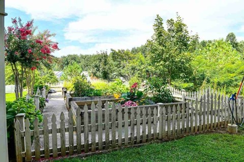 A wooden fence with flowers in the front yard.