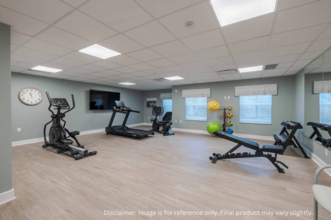 A spacious gym with a variety of exercise equipment and a clock on the wall.