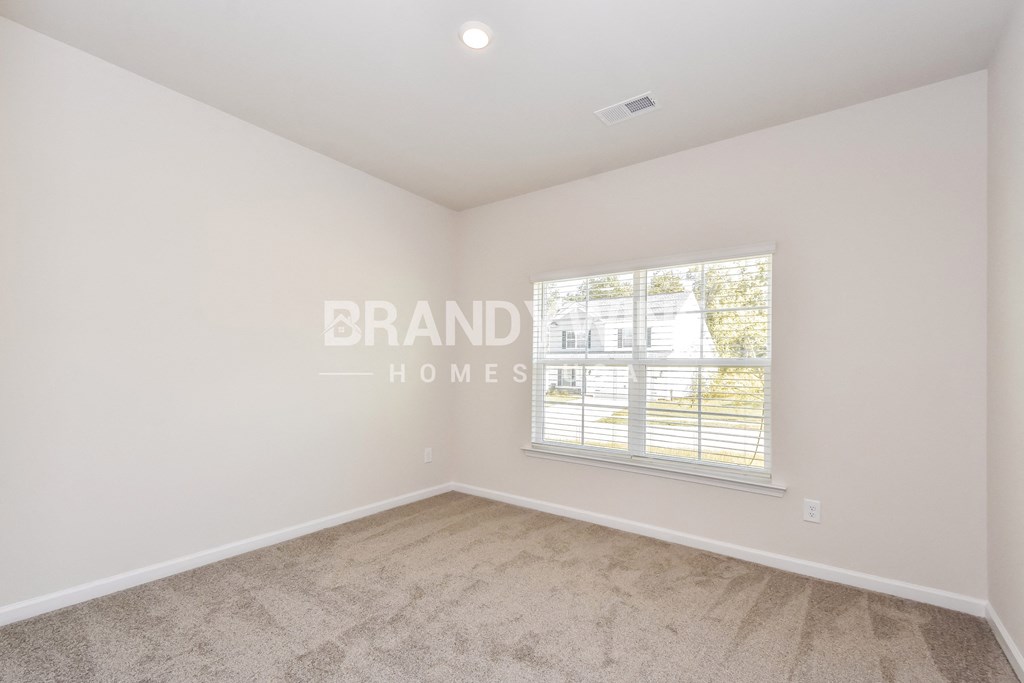 a bedroom with a large window and carpeted floor