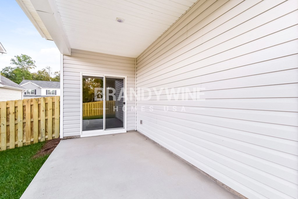a backdoor patio into a white house with a wooden fence