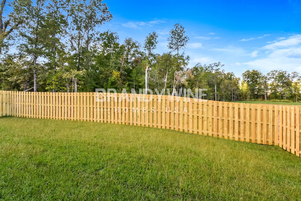 wooden fence around a yard with green grass and trees