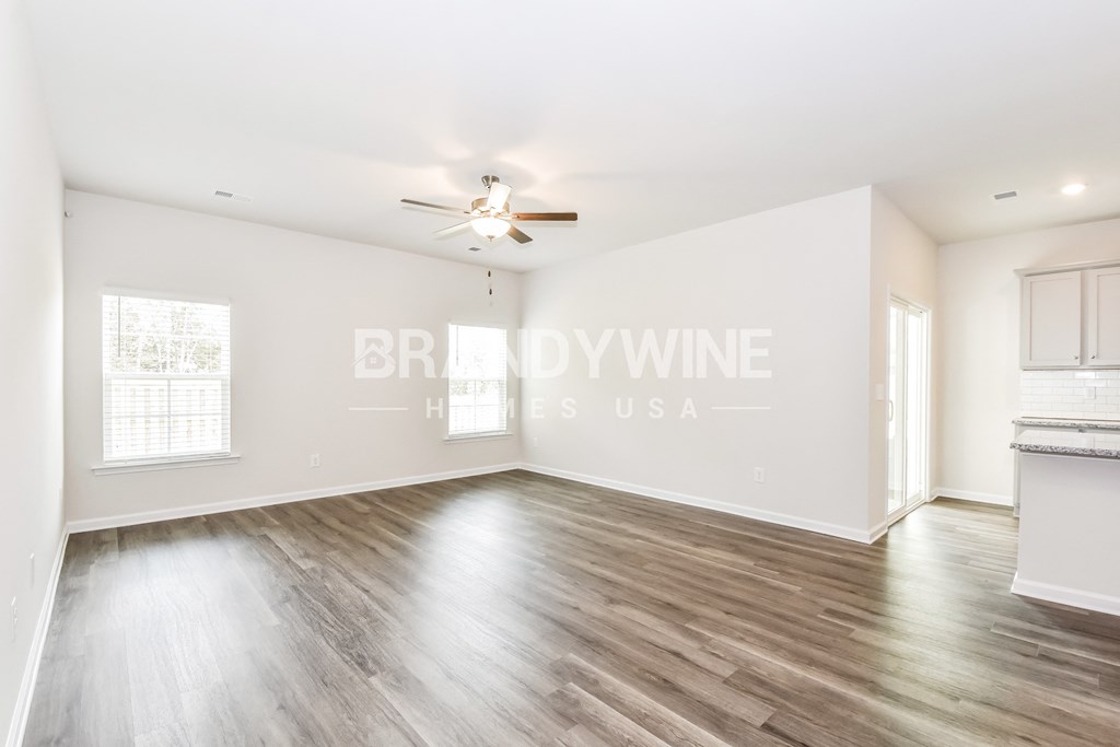 an empty living room with white walls and a ceiling fan
