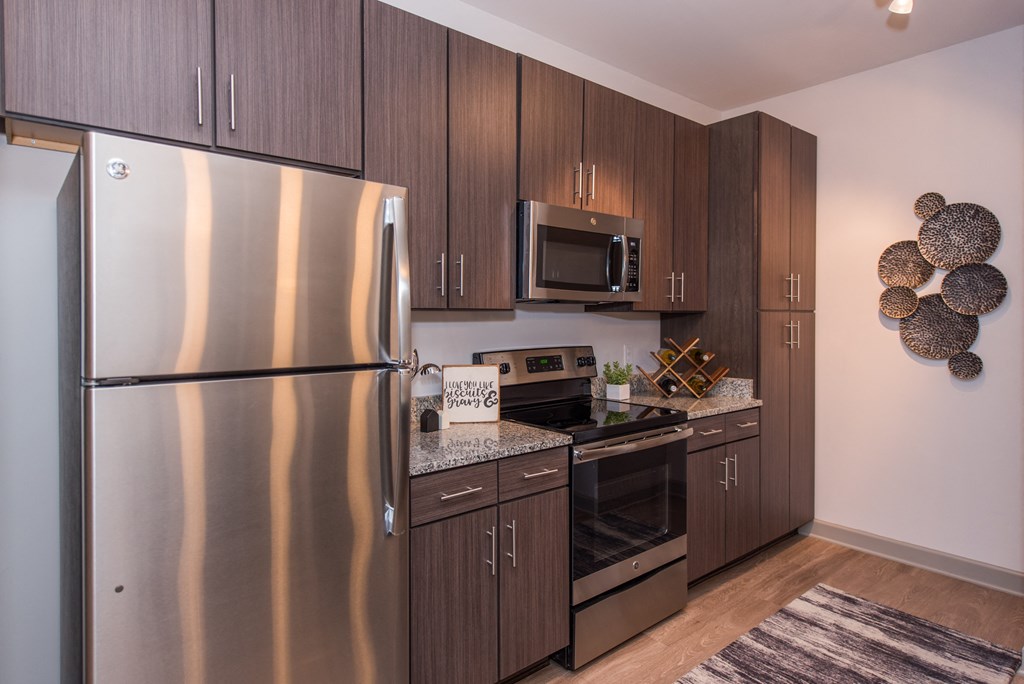 a kitchen with dark wood cabinets and stainless steel appliances at The Whitworth, Virginia, 23185